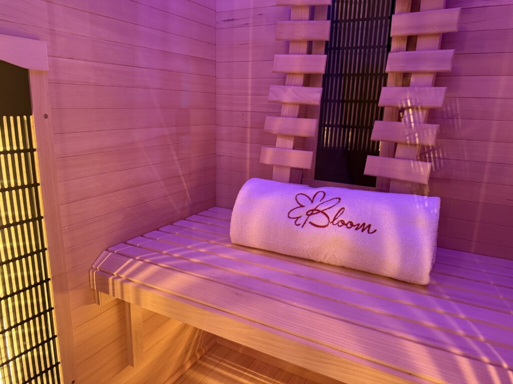 Interiorul saunei cu infraroșu de la Bloom Pilates & Spa Bragadiru, cu bancă din lemn și prosop personalizat Bloom